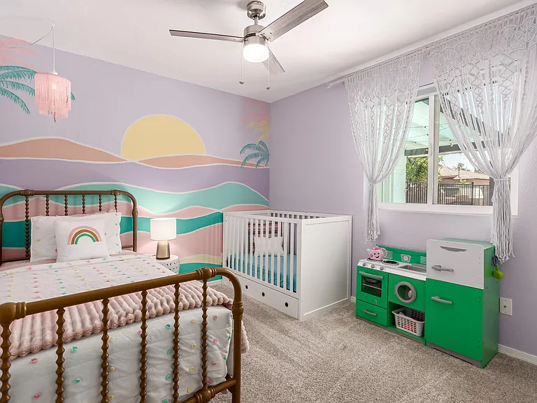 Kid's room with twin bed and crib, books and toys.