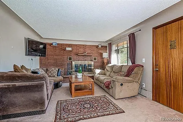 Living room with Brick facade and woodburning fireplace with brass fittings. Front door