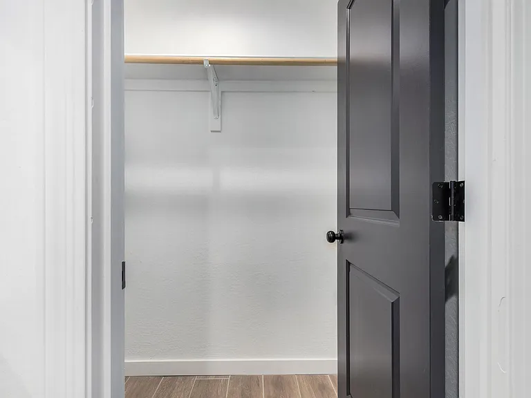 Walk-in closet with a hanging rod and upper shelf, offering practical storage space for clothing and essentials.