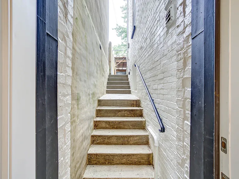 The first bedroom includes access to the rear staircase, which is primarily used for trash and recycling and serves as an additional emergency exit, with the patio at the top reserved for the upstairs residence.