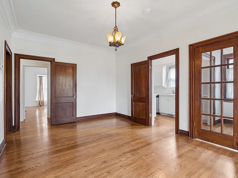 Formal dining room looking toward dining nook on right. Kitchen entrance door in middle. Left door leads to hallway that connects to bedroom 2