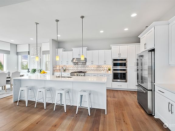 Mia Cucina kitchen is a dream with an expansive waterfall center island, upgraded gas range, convection oven combo/double ovens, and a counter depth French door refrigerator.>