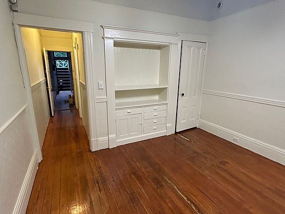 Living space, view toward front door and building entry. Built-in cabinet, closet.