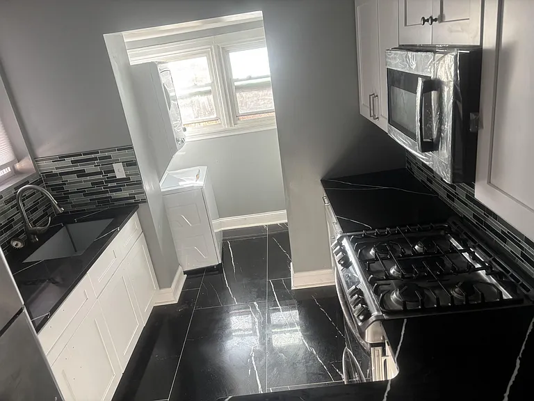 Efficient galley kitchen with ample cabinet storage, gas range, built-in microwave, and a window for natural light.