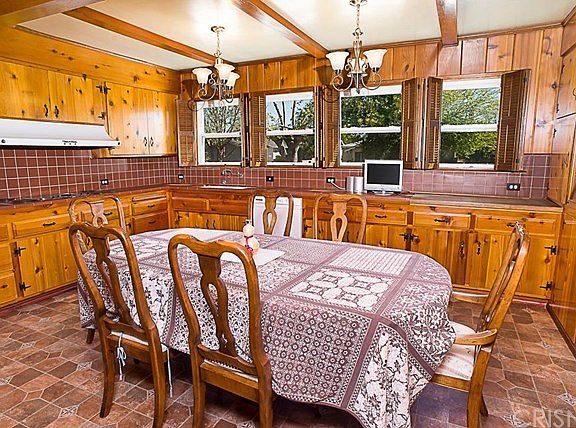 The large eat-in country kitchen features loads of gorgeous knotty pine cabinetry from the era, tile