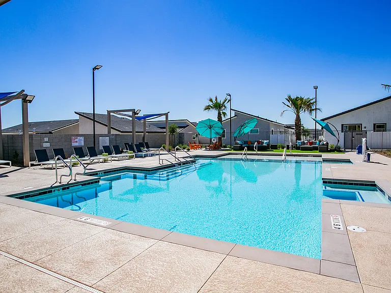Relax by the poolside in a serene, sun-filled environment perfect for leisure and comfort.