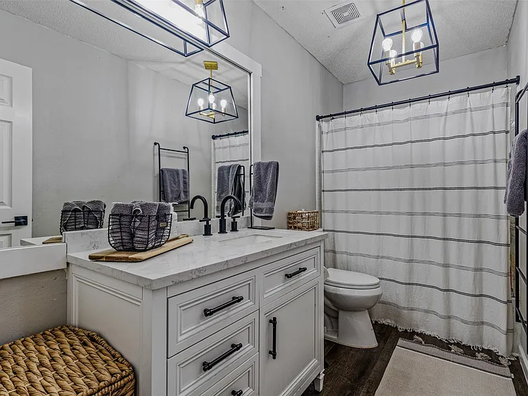 Bathroom featuring a white vanity with a light-toned countertop, black matte fixtures, and wood-finish flooring