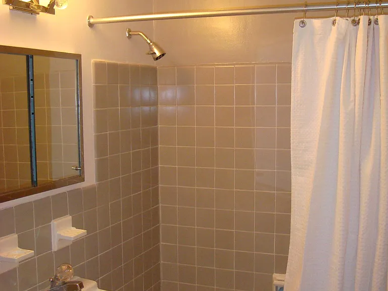 Tiled bathroom with cast iron tub/shower.