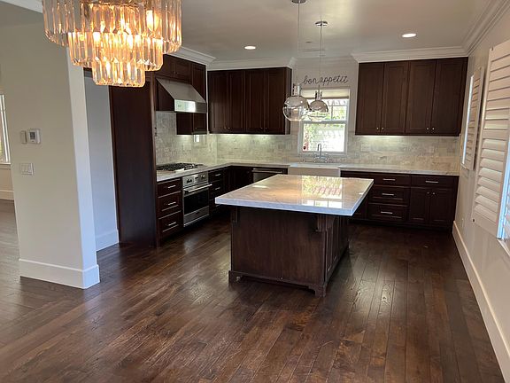 Large kitchen with carrera marble countertops and backsplash, high-end lighting fixtures, and built-in Viking range, dishwasher, and microwave.