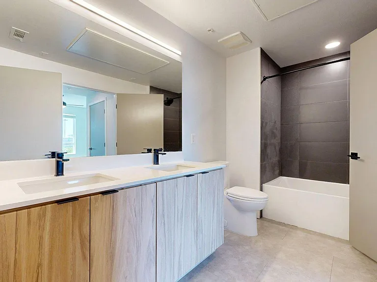 Apartment Bathroom with Large Soaking Tub, LED Vanity Mirror and Wood-Style Flooring.