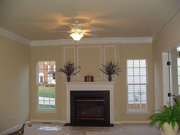 Family Room with gas log fireplace, new carpet, molding and new ceiling fan.