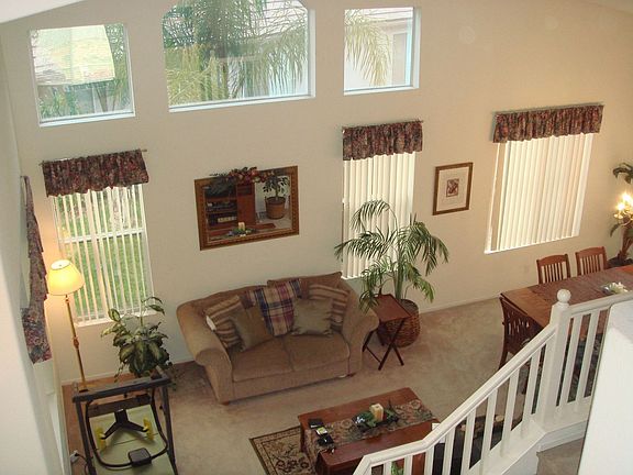 Formal living room has multiple windows and high ceilings.
