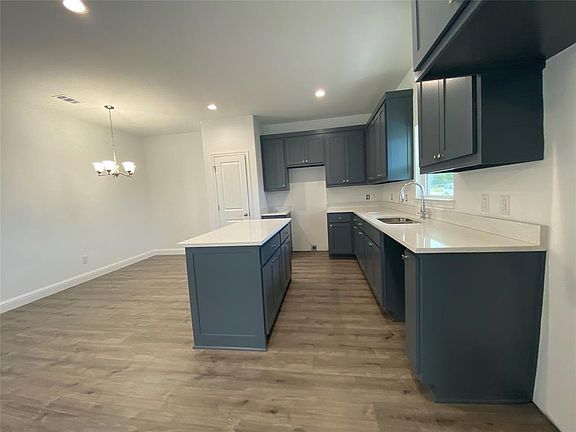 Kitchen with light wood-style floors, recessed lighting, a center island, light stone countertops, and decorative light fixtures