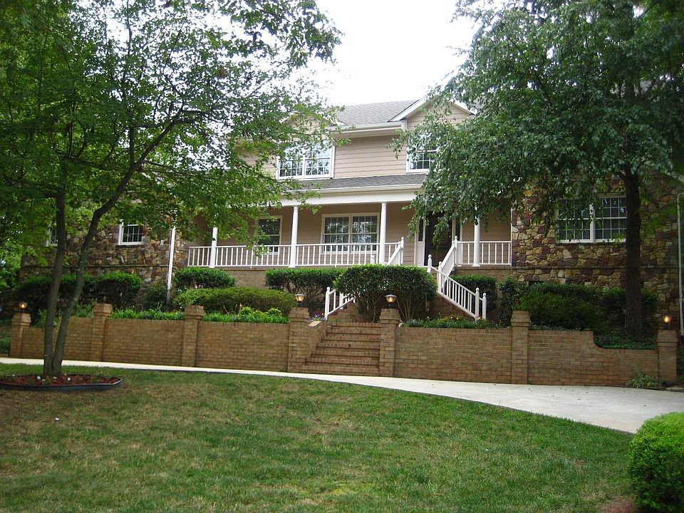 Grand entrance with full circular driveway, brick steps, and beautiful natural