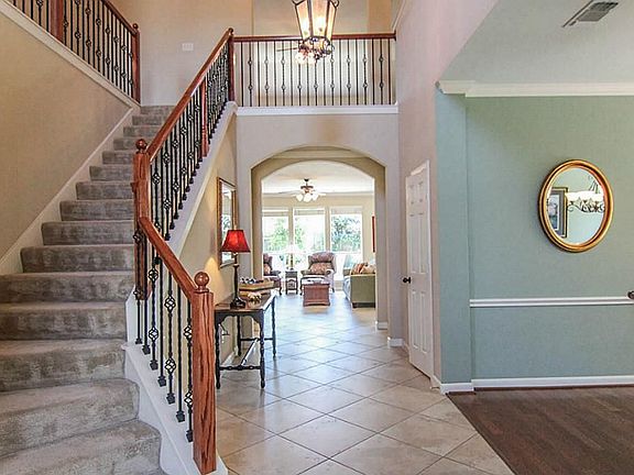Dramatic entry with chandelier, wrought iron railings on the curved staircase and a view to the gorgeous landscaping in the backyard. Upgraded 18" tile floor laid in a diagonal pattern makes the rooms feel larger.