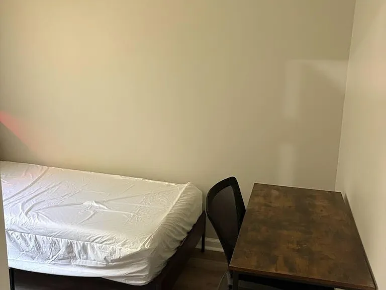 Private bedroom set up with a bed and dedicated desk area for studying or remote work, plus durable flooring.