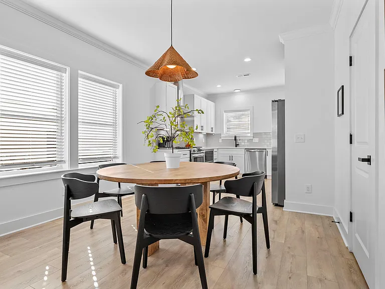 Open dining area with round table seating and easy flow into the kitchen with white cabinetry and stainless appliances.