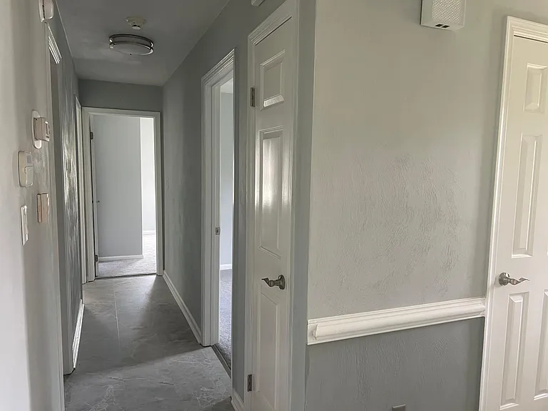 Hallway from foyer with coat closet that also features a spacious linen closet, entrance to the hall bath and 3 bedrooms.