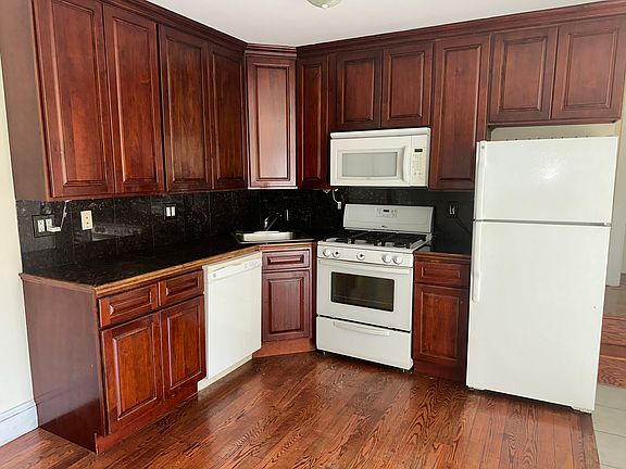 Kitchen - 1st Floor - Open Concept Kitchen with white appliances, dark hardwood / wood-style floors, tasteful backsplash, and sink
