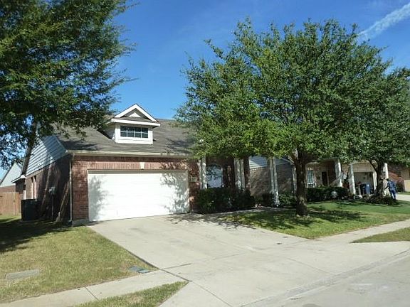 View of property hidden behind natural elements featuring a front lawn and a garage