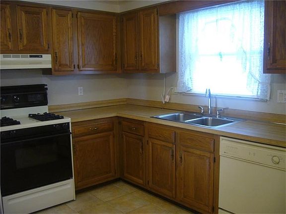 Close up of cabinets, and a window and a view of the flat park like yard.