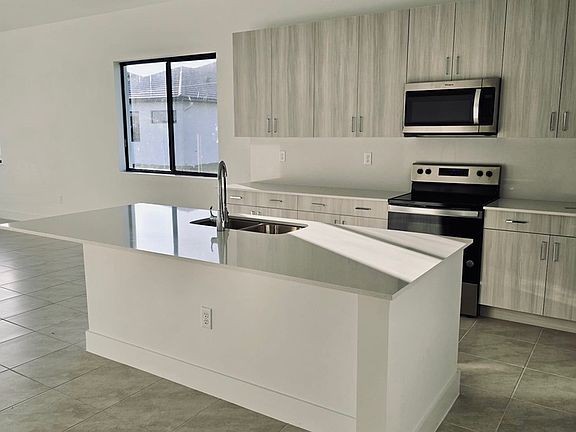 upgraded kitchen features quartz countertops, stainless steel appliances, and impact windows