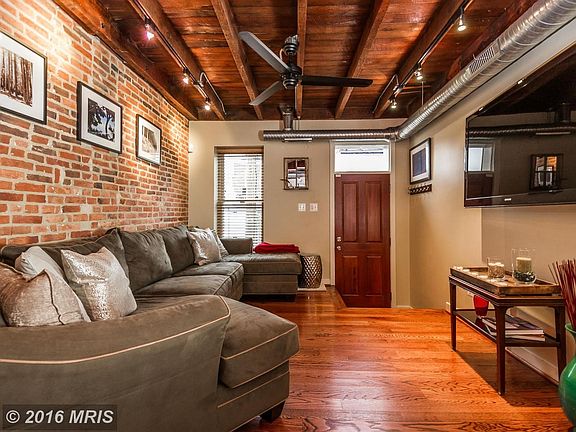 Living room features exposed brick and beams
