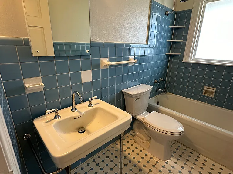 Original cast iron tub and sink with built in cabinet space behind mirror.