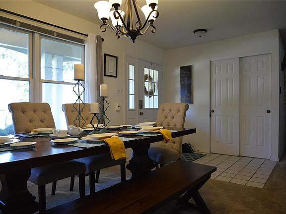 Formal dining area with large, double windows and hanging light fixture.