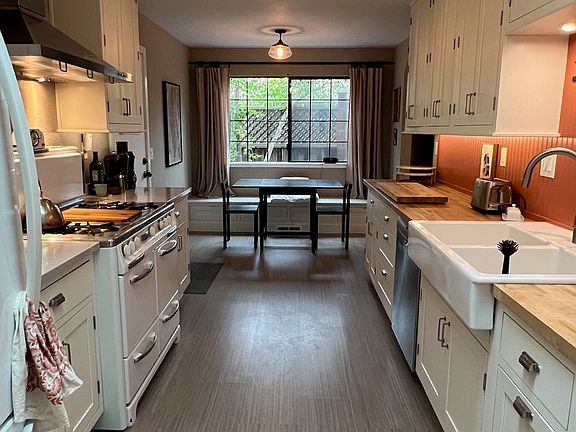 Eat-in kitchen with classic gas Wedgewood range, baquet with storage, and dining area.
