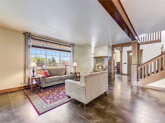Wide open living area with wood burning fireplace finished in natural stone and gold-plated doors.