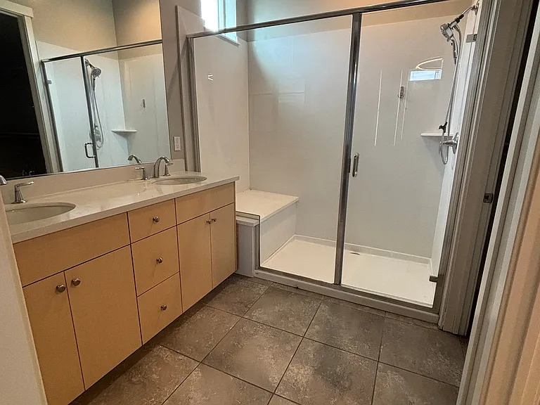Large primary bathroom with shower and dual sinks on countertop.