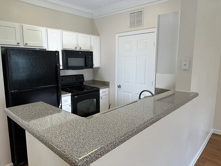 Modern kitchen with sleek countertops, white cabinetry, and black appliances creating a stylish cooking space. Modern kitchen with sleek countertops, white cabinetry, and black appliances creating a stylish cooking space.