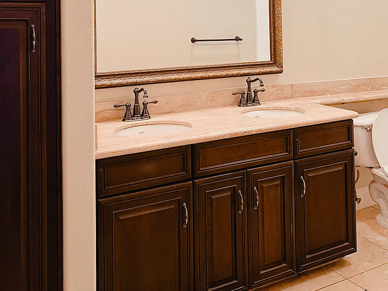 Bathroom with double sinks and dark wood cabinets at Carmel Heights Apartments in San Diego, California.