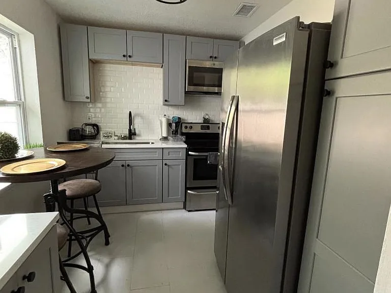 Efficient kitchen with ample cabinetry, stainless steel appliances, and a bistro dining nook beside the window.