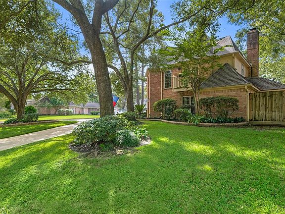 View of the circular driveway, trees and extended brick border. Balcony looks out from the secondary bedroom onto Oakcroft Drive.