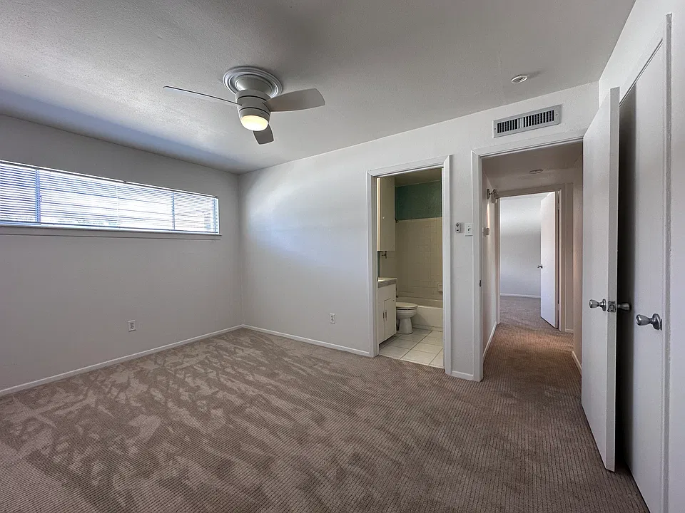 A view of of the West Bedroom with its bathroom and windows facing north. The hallway between the bedrooms can also be seen here.