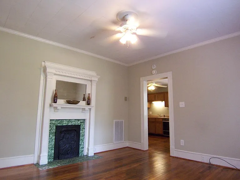 Living room w/ firplace mantel, hardwood floors, ceiling fan