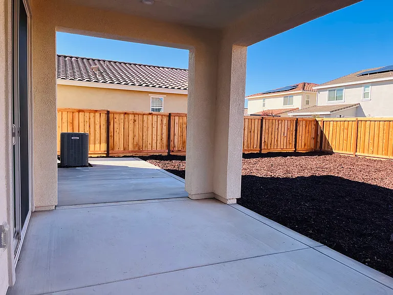 Backyard with extended concrete and low maintenance mulch