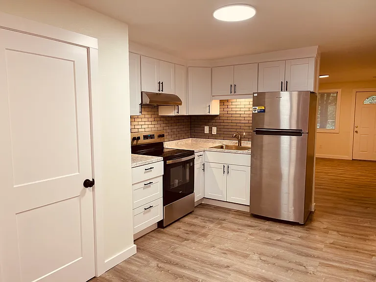 Large kitchen with stainless steel appliances, modern white cabinets and designer subway tile backsplash.