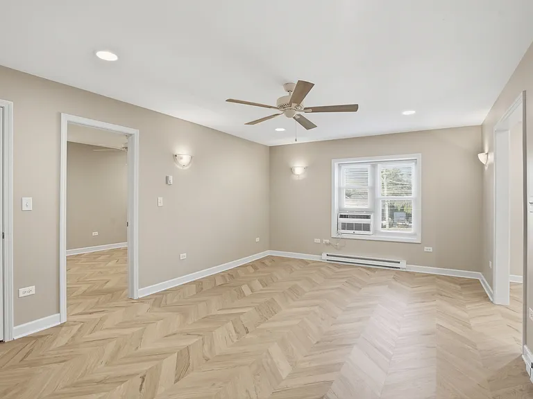 Spacious living room with ceiling fan between kitchen and bedroom.