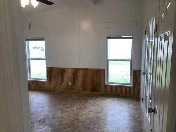 Partial view of Primary Bedroom. Primary Bathroom through French Doors to the right. Solar screens and Venetian blinds on every window to reduce utility costs. Board above each window to attach curtain rods.