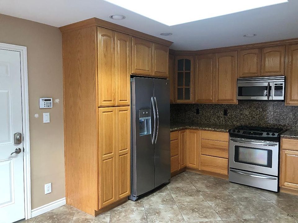 Kitchen with stainless appliances, including new refrigerator.