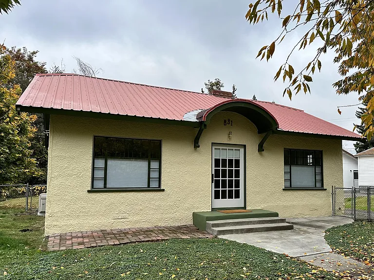 Valencia Cottage's exterior showcases its 1926 charm: a curved entry, large original windows with divided lites, and a giant original front door.