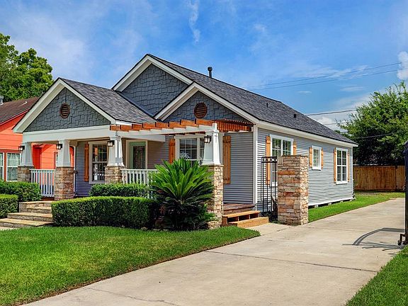 TASTEFUL LANDSCAPING ADORNS THE FRONT YARD AND THE DRIVEWAY FEATURES AN IRON GATE.