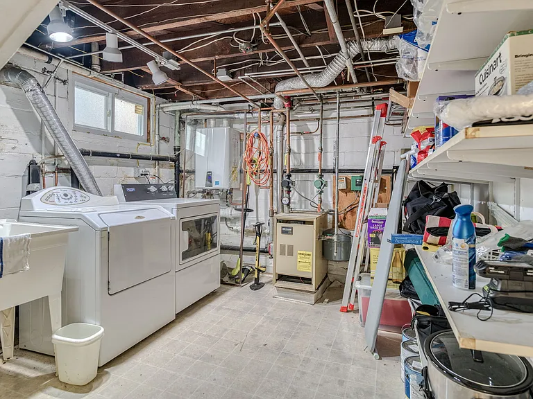 Washer, dryer, utility sink, storage area in unfinished basement.