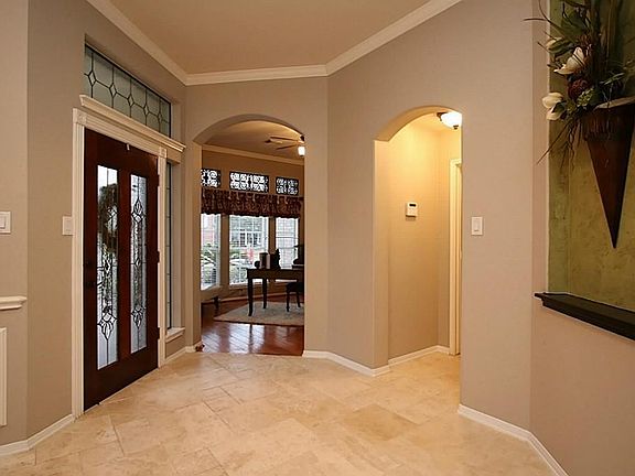 Crown molding and arched doorways great you. Neutral paint. Front room could be study or additional living space. Right doorway leads to powder bath. Recessed wallspace for your art work.