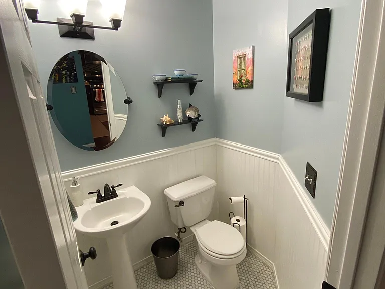 Powder room on main level with marble floors, pedestal sink, and wainscoting.