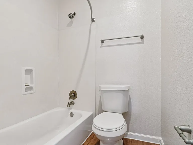 Modern bathroom featuring a sleek white bathtub and toilet with a towel bar, perfect for relaxation. Modern bathroom featuring a sleek white bathtub and toilet with a towel bar, perfect for relaxation.