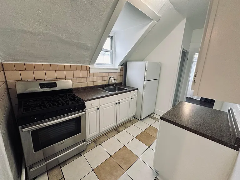 Kitchen, left second back entry staircase to back yard, bedroom in the back. Tile floors and backsplash.
Fridge, gas stove, sink. North facing window.
